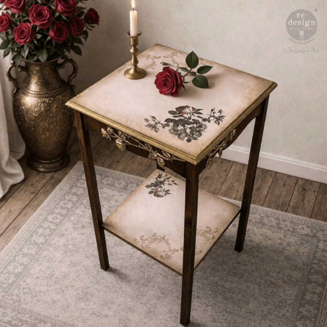 Decorative side table with floral design, candle, and vase of roses in a room setting.