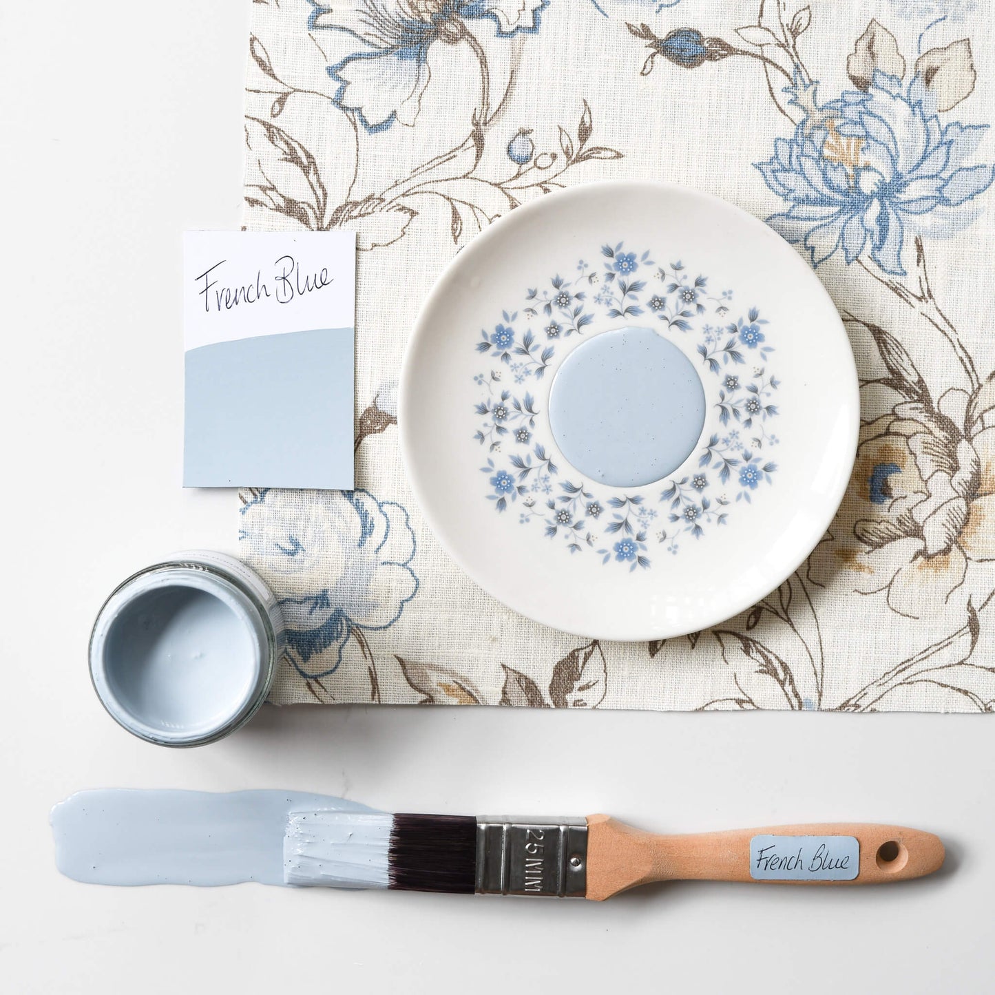 Fabric mood board with paintbrush dipped in a 120ml pot of Blake & Taylor French Blue Chalk Furniture Paint