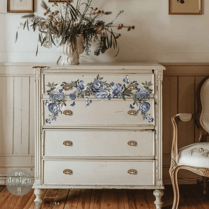 Vintage dresser with floral decoupage on a wooden floor, surrounded by decorative elements.