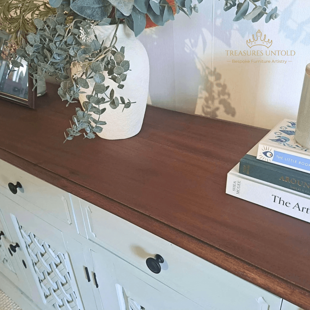 A close-up of wooden console cabinet painted Blake & taylor Paint, colour Willow with a dark brown wood top, styled with a white vase of eucalyptus and a stack of books. 